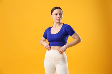 Woman in sportswear posing on orange background