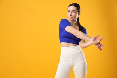 Woman in sportswear posing on orange background, space for text