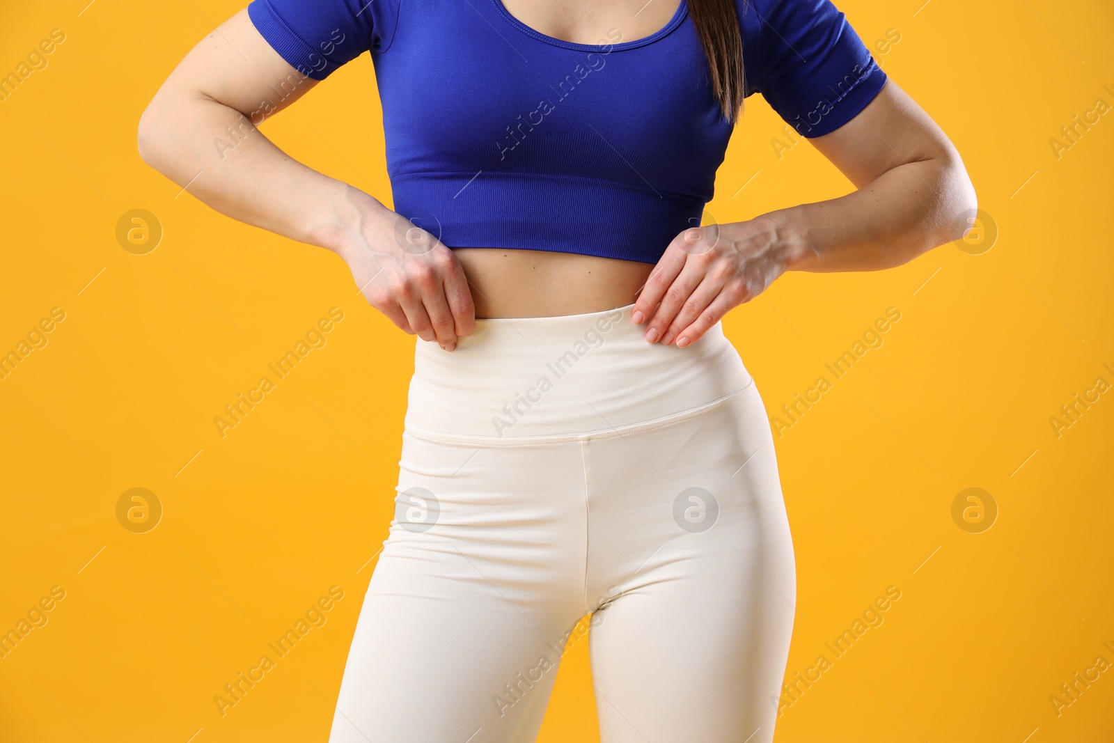 Photo of Woman in sportswear posing on orange background, closeup