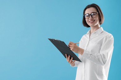 Young secretary with clipboard taking notes on light blue background. Space for text