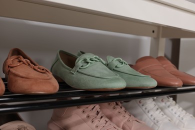 Photo of Stand with different stylish shoes indoors, closeup