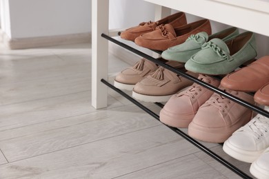 Photo of Stand with different stylish shoes indoors, closeup. Space for text