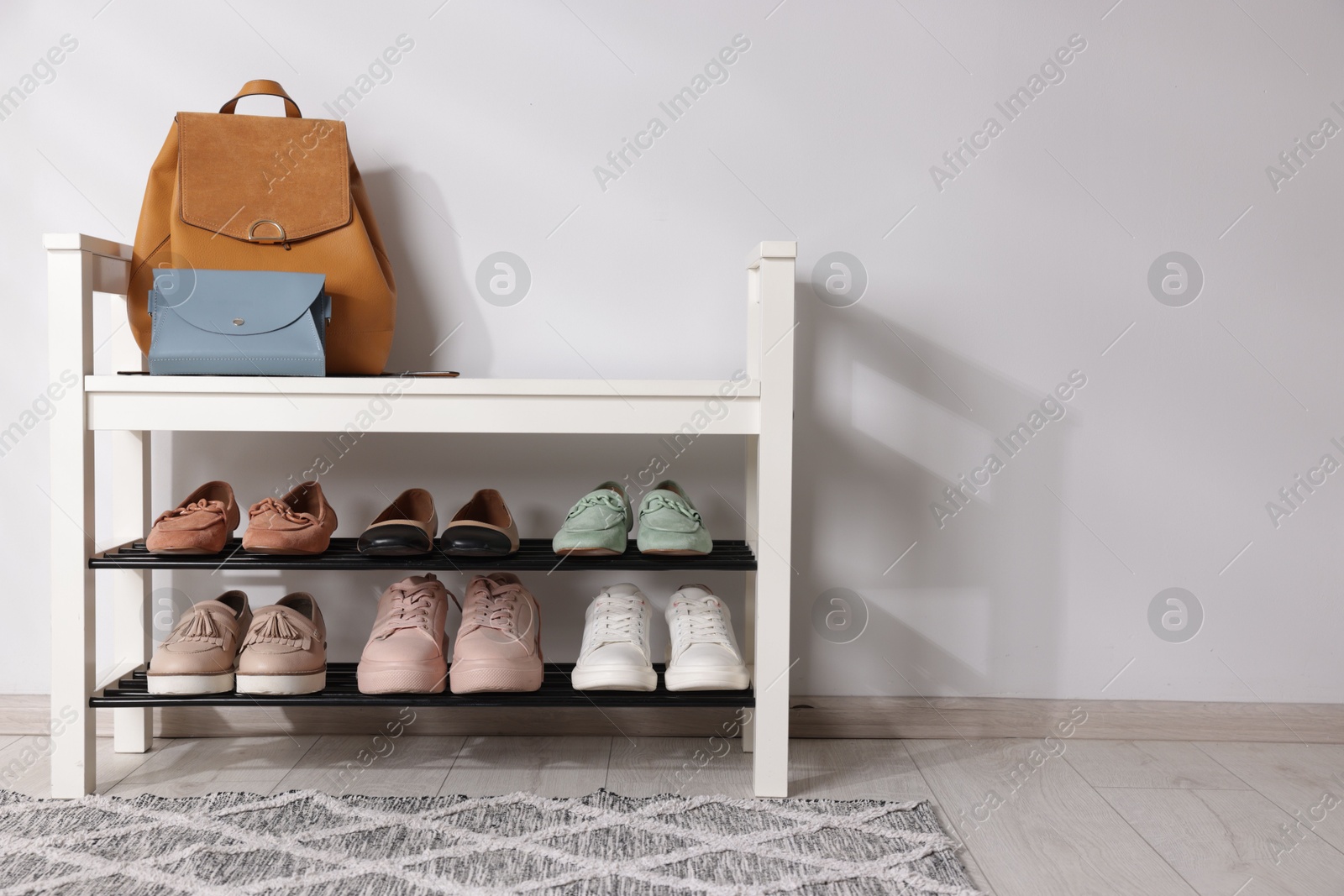 Stand with different stylish shoes and bags indoors. Space for text Photo of Stand with different stylish shoes and bags indoors. Space for text