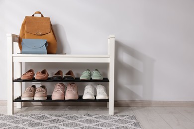 Photo of Stand with different stylish shoes and bags indoors. Space for text
