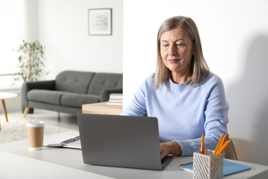 Photo of Woman learning online using laptop at table indoors. Self-study