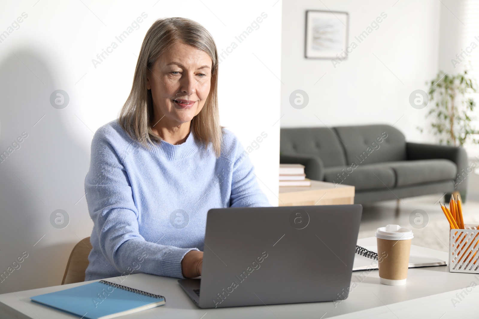 Photo of Woman learning online using laptop at table indoors. Self-study