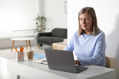 Photo of Woman learning online using laptop at table indoors. Self-study