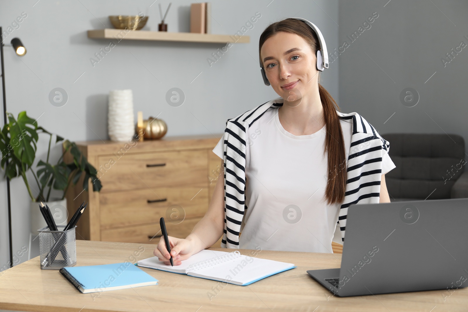 Photo of Woman taking notes during online lesson at table indoors. Self-study