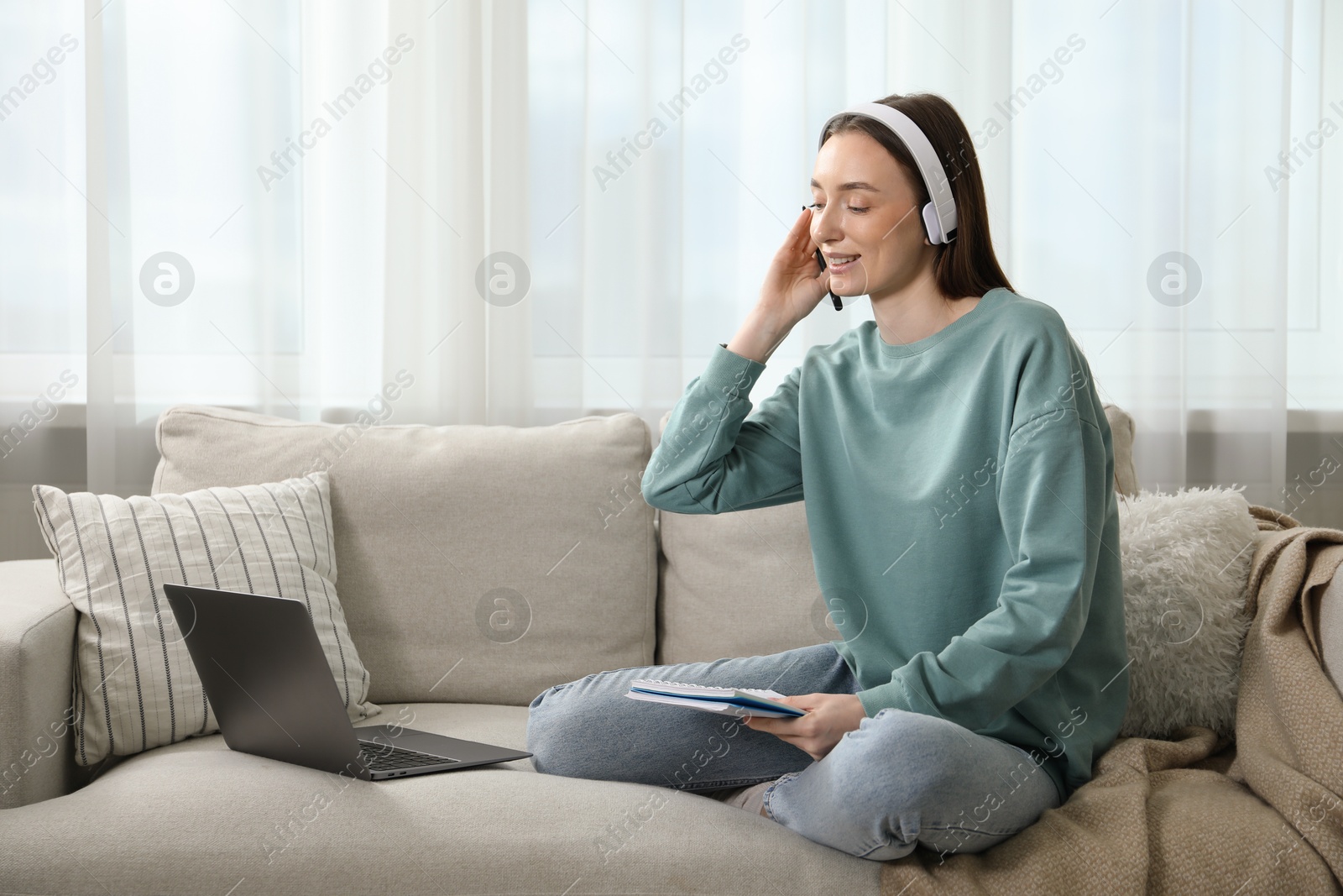 Photo of Smiling woman learning online using laptop on sofa indoors. Self-study