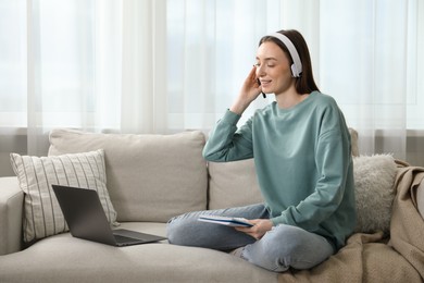 Photo of Smiling woman learning online using laptop on sofa indoors. Self-study