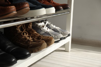 Photo of Shoe storage bench with different footwear indoors, closeup. Space for text