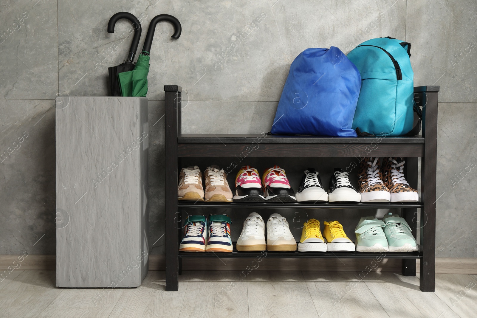 Shoe storage bench with different footwear, backpack, sport's bag and umbrellas indoors Photo of Shoe storage bench with different footwear, backpack, sport's bag and umbrellas indoors