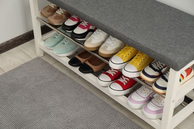 Photo of Shoe storage bench with different footwear indoors, closeup