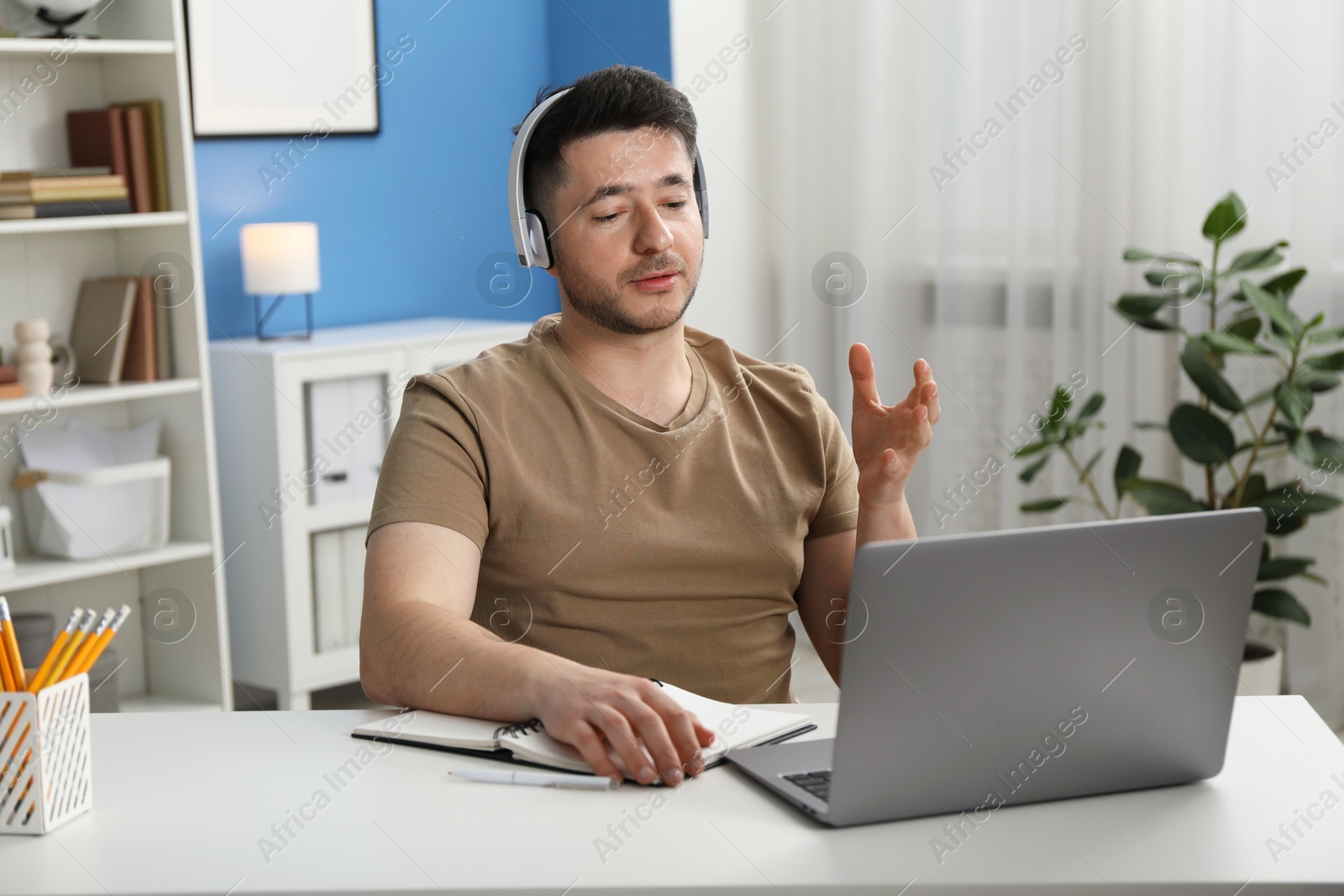 Photo of Man having online lesson with teacher via laptop at desk indoors