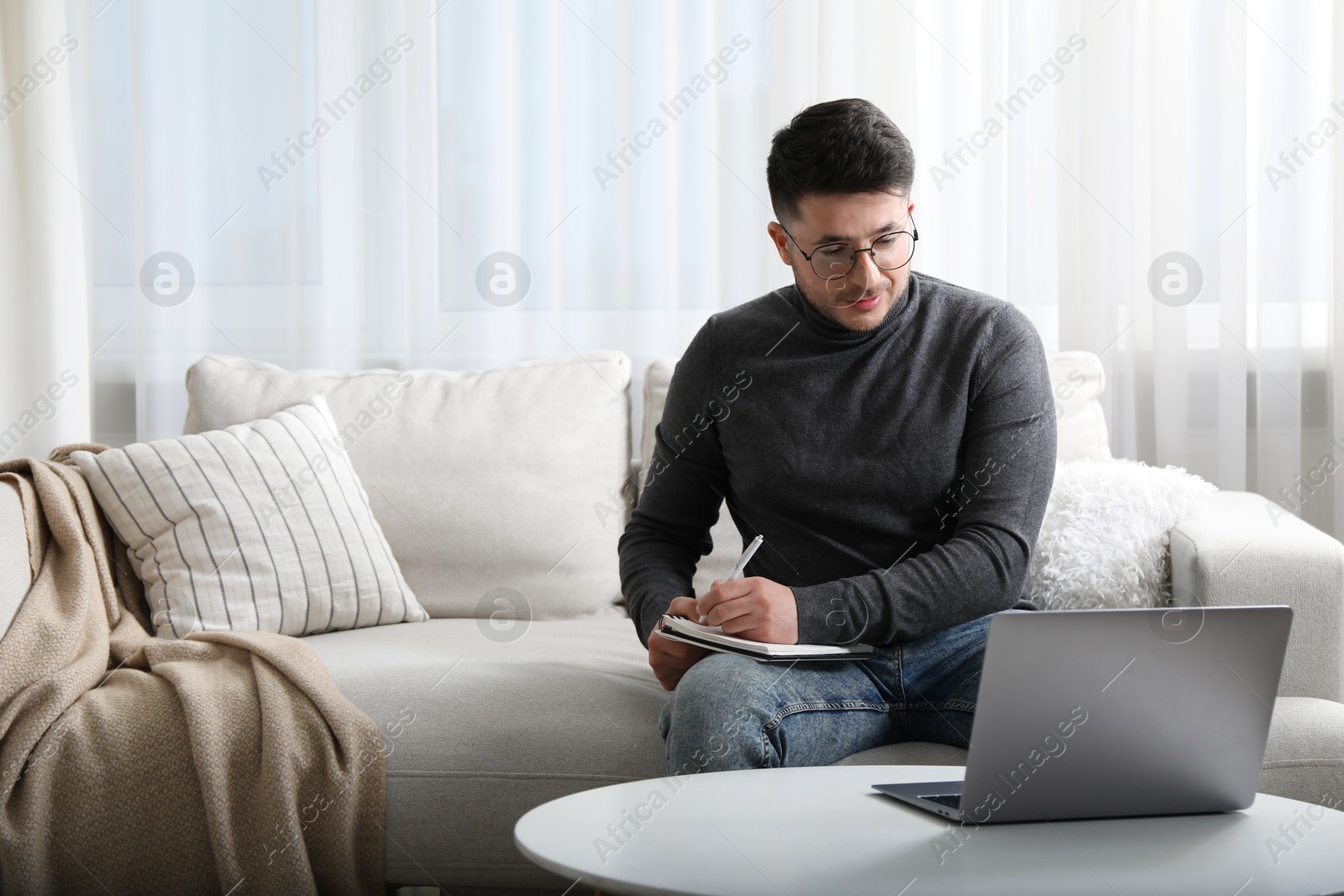 Photo of Man taking notes during online lesson at table indoors, space for text. Self-study