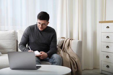 Man taking notes during online lesson at table indoors, space for text. Self-study