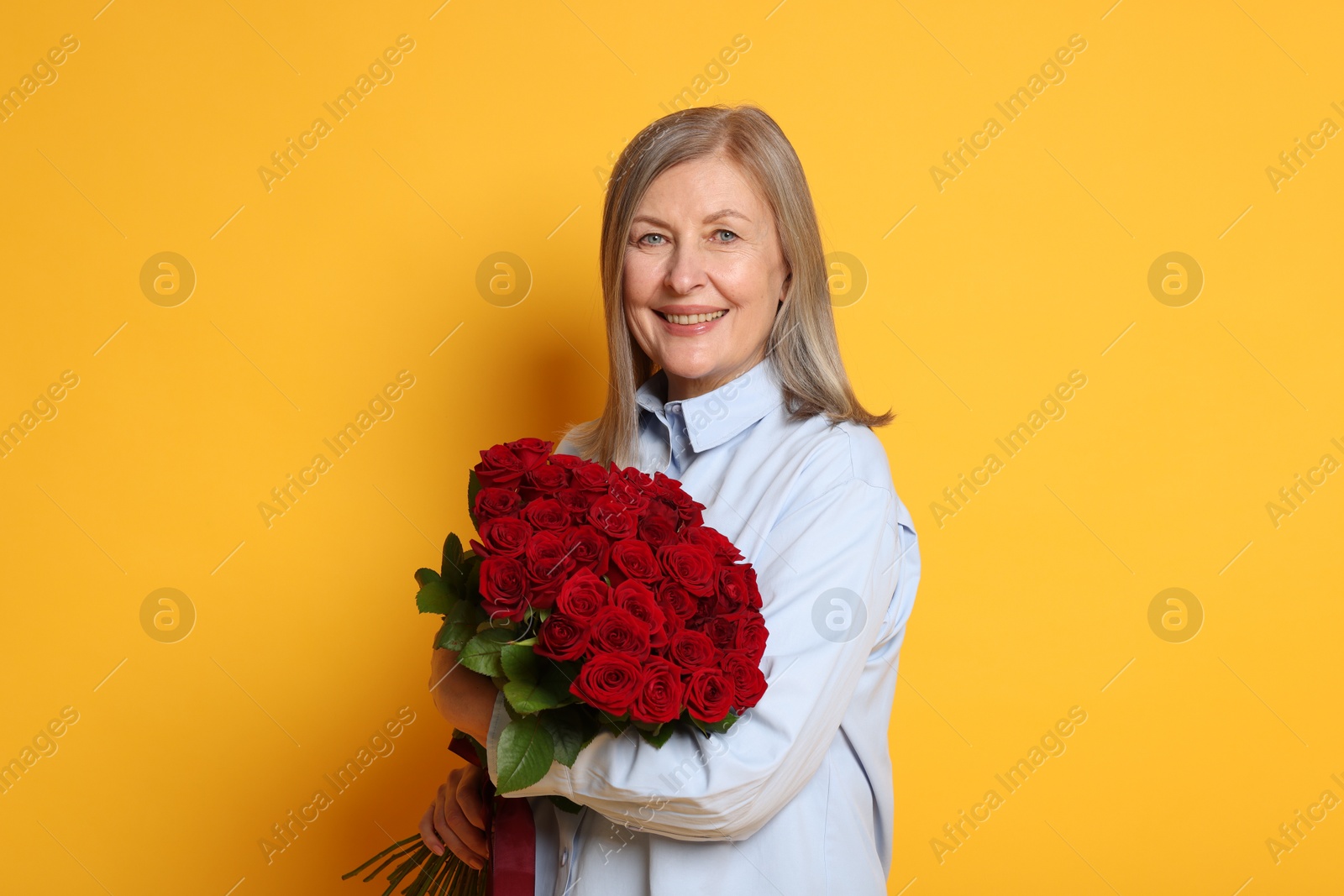 Photo of Smiling woman with bouquet of roses on yellow background