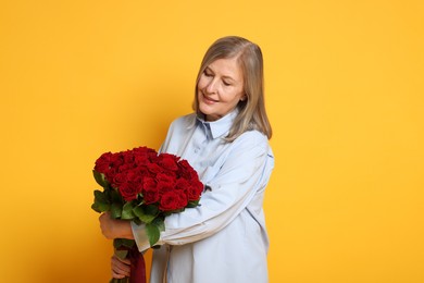 Smiling woman with bouquet of roses on yellow background