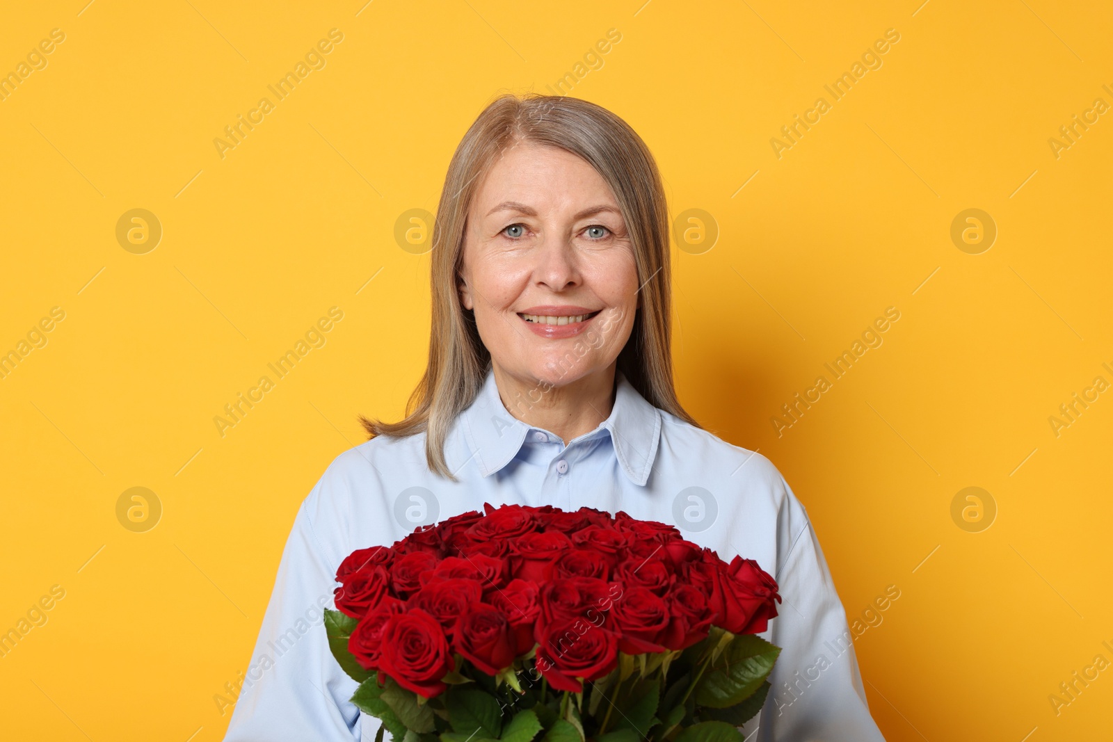 Photo of Smiling woman with bouquet of roses on yellow background