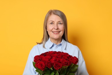 Smiling woman with bouquet of roses on yellow background