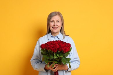 Photo of Smiling woman with bouquet of roses on yellow background