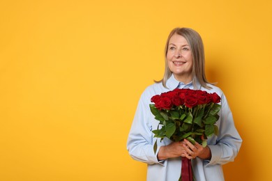 Smiling woman with bouquet of roses on yellow background. Space for text