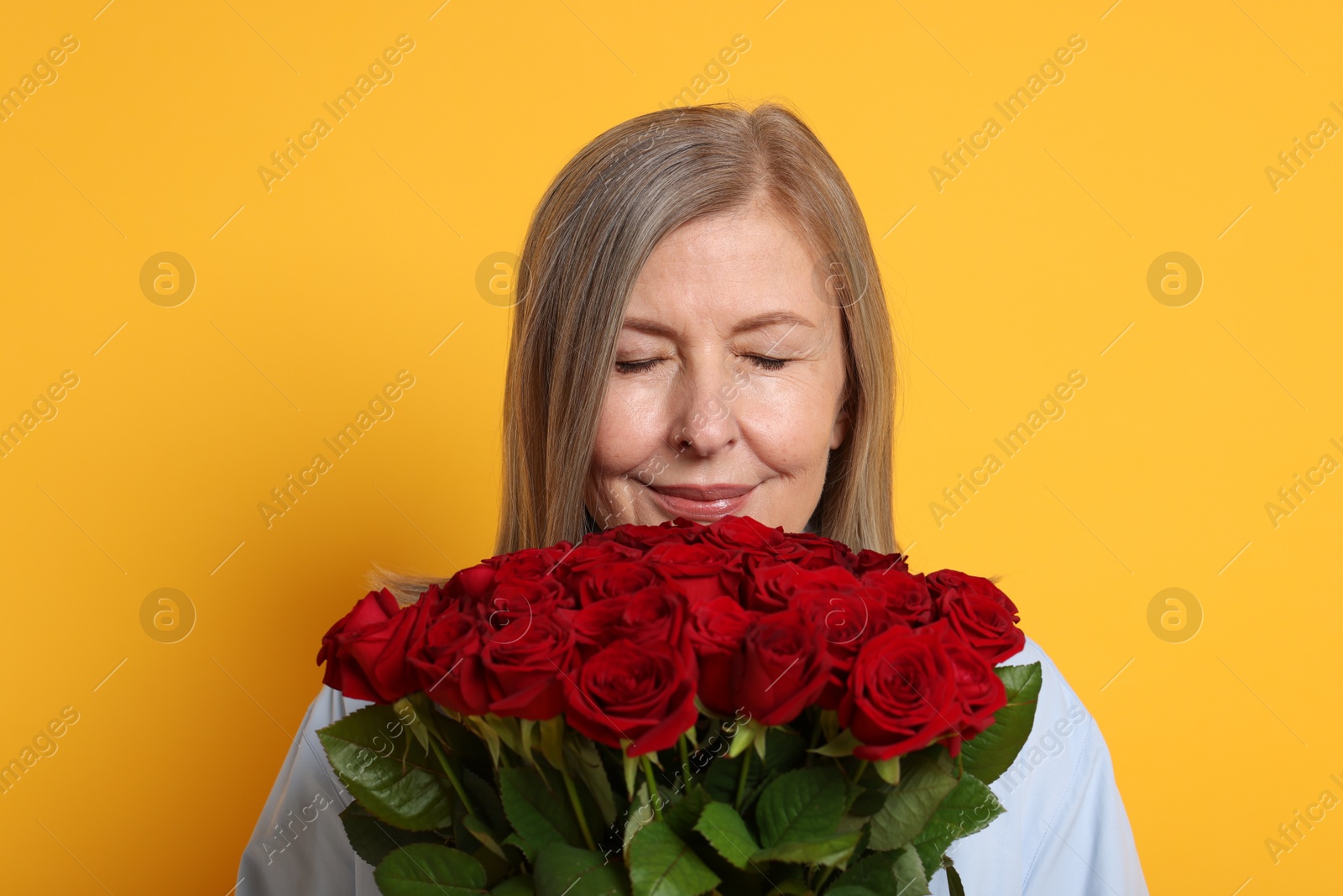 Photo of Woman with bouquet of roses on yellow background