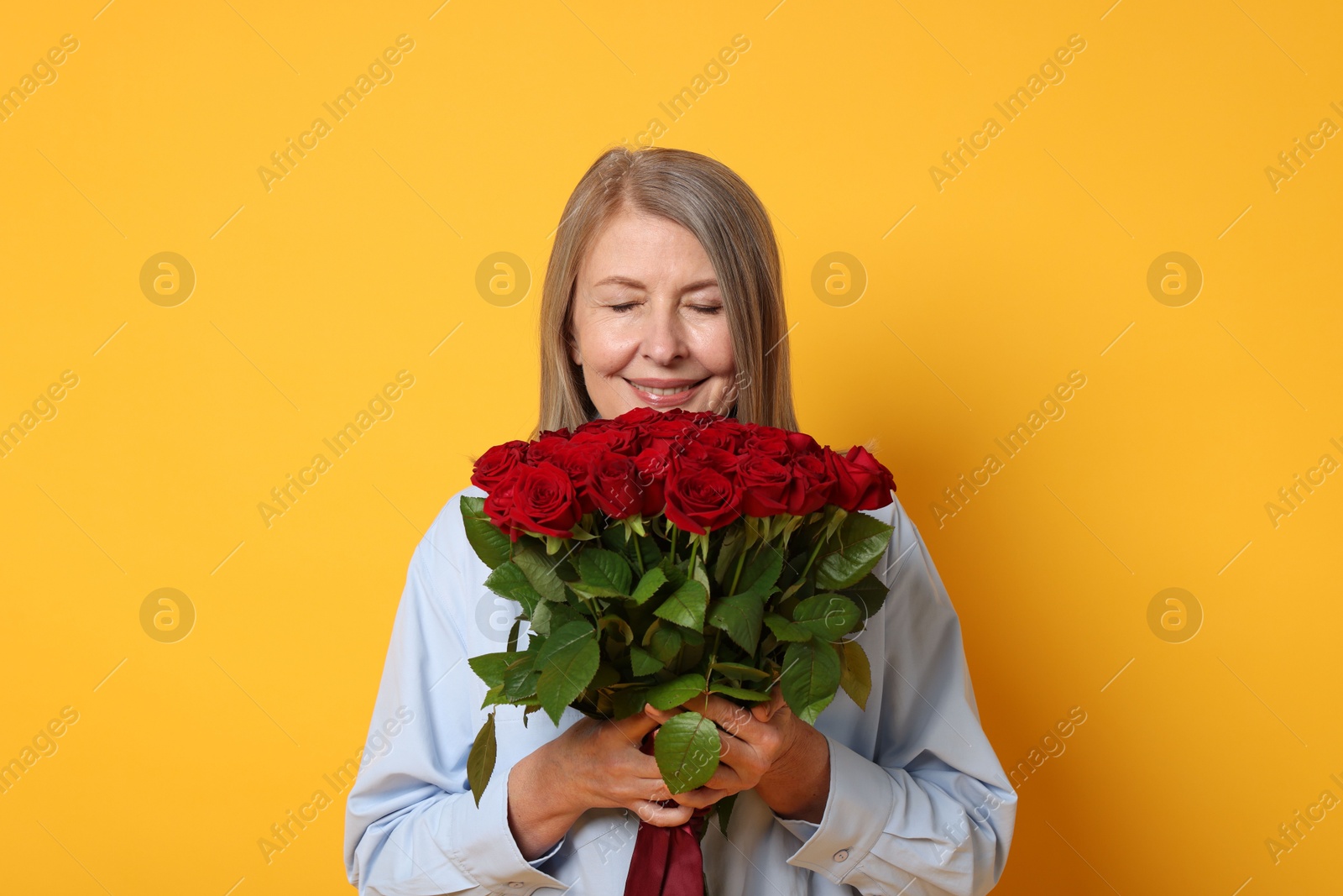 Photo of Smiling woman with bouquet of roses on yellow background