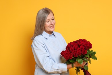 Smiling woman with bouquet of roses on yellow background