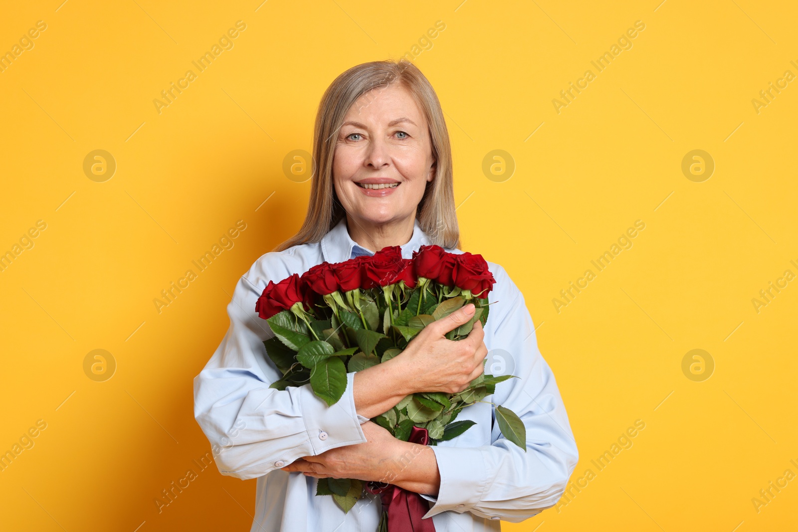 Photo of Smiling woman with bouquet of roses on yellow background