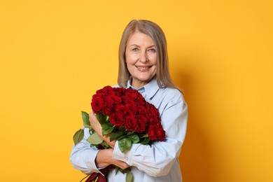 Photo of Smiling woman with bouquet of roses on yellow background