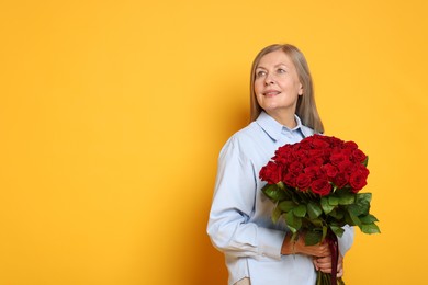 Photo of Smiling woman with bouquet of roses on yellow background. Space for text