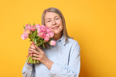 Smiling woman with bouquet of tulips on yellow background