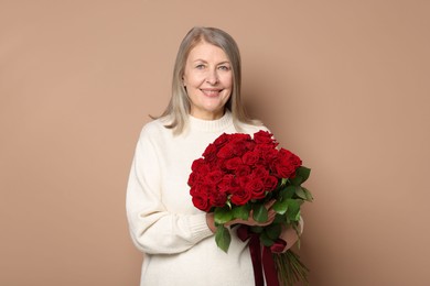 Smiling woman with bouquet of roses on beige background