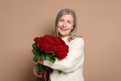 Smiling woman with bouquet of roses on beige background