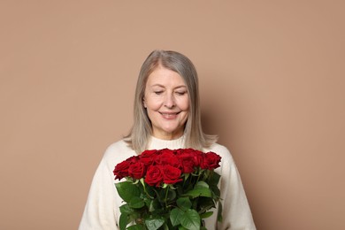 Smiling woman with bouquet of roses on beige background