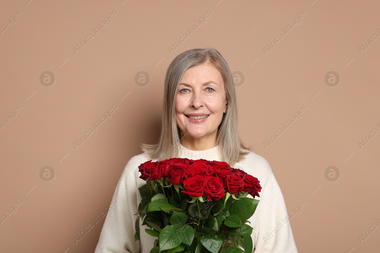 Photo of Smiling woman with bouquet of roses on beige background