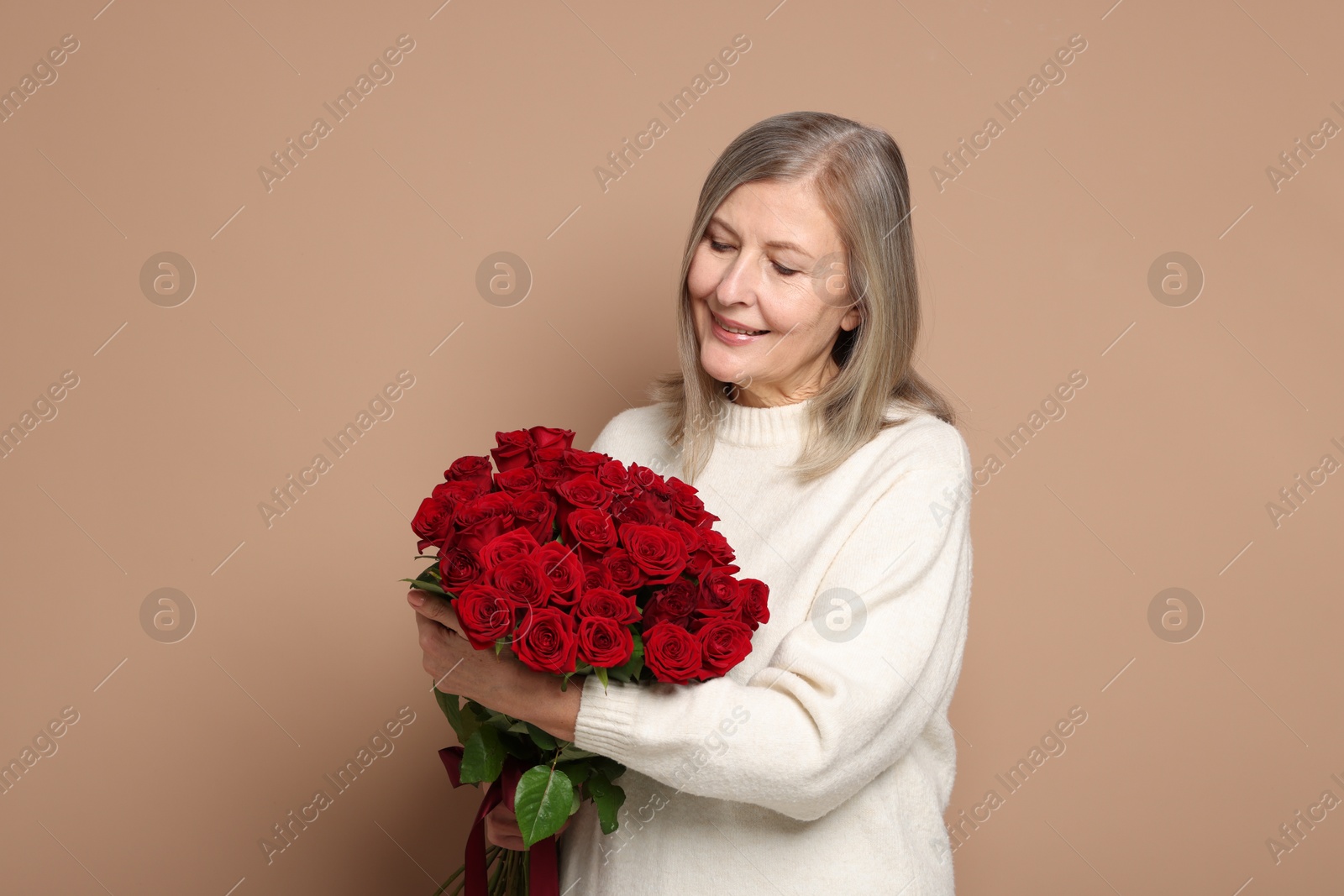 Photo of Smiling woman with bouquet of roses on beige background