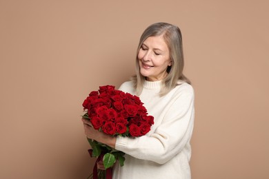 Smiling woman with bouquet of roses on beige background