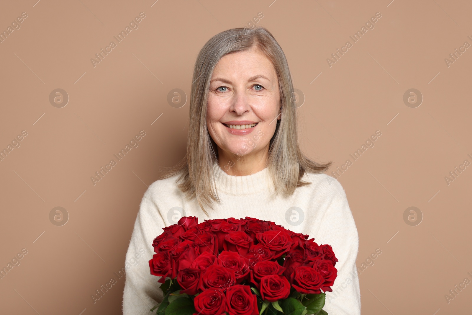 Photo of Smiling woman with bouquet of roses on beige background