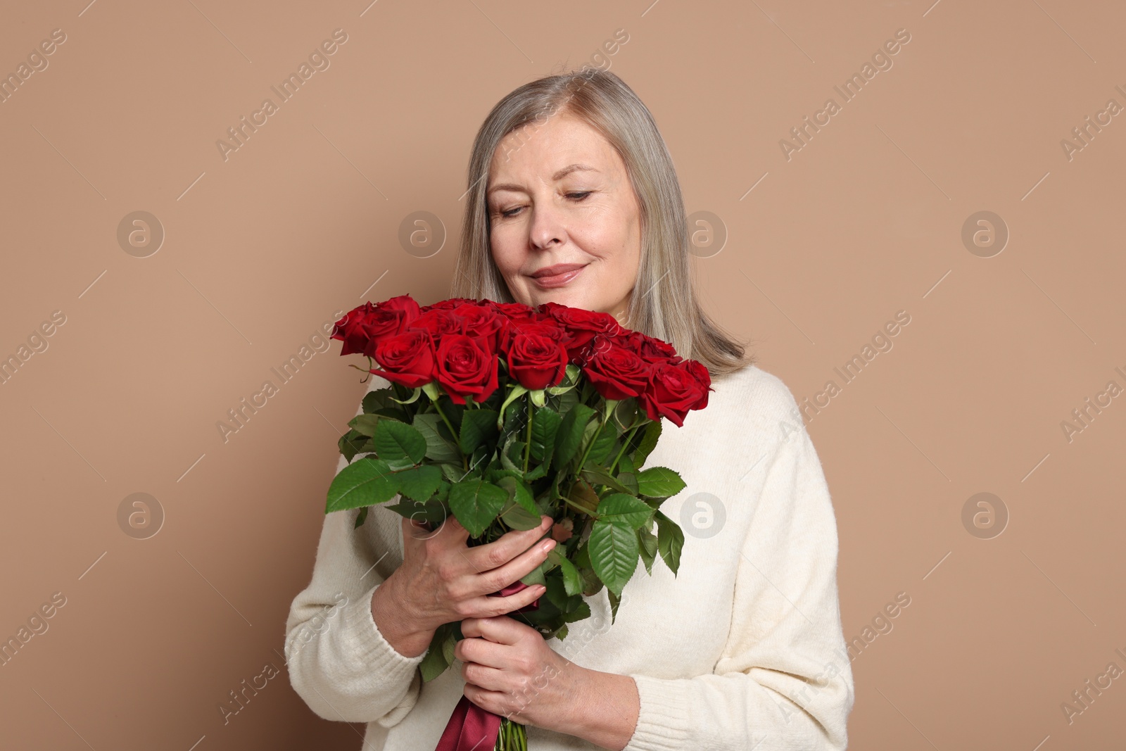 Photo of Beautiful woman with bouquet of roses on beige background