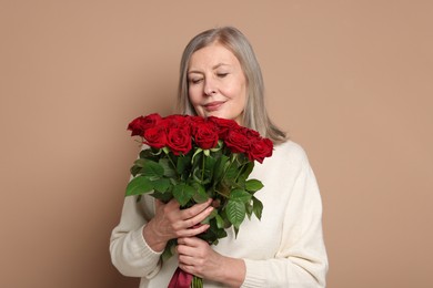 Beautiful woman with bouquet of roses on beige background