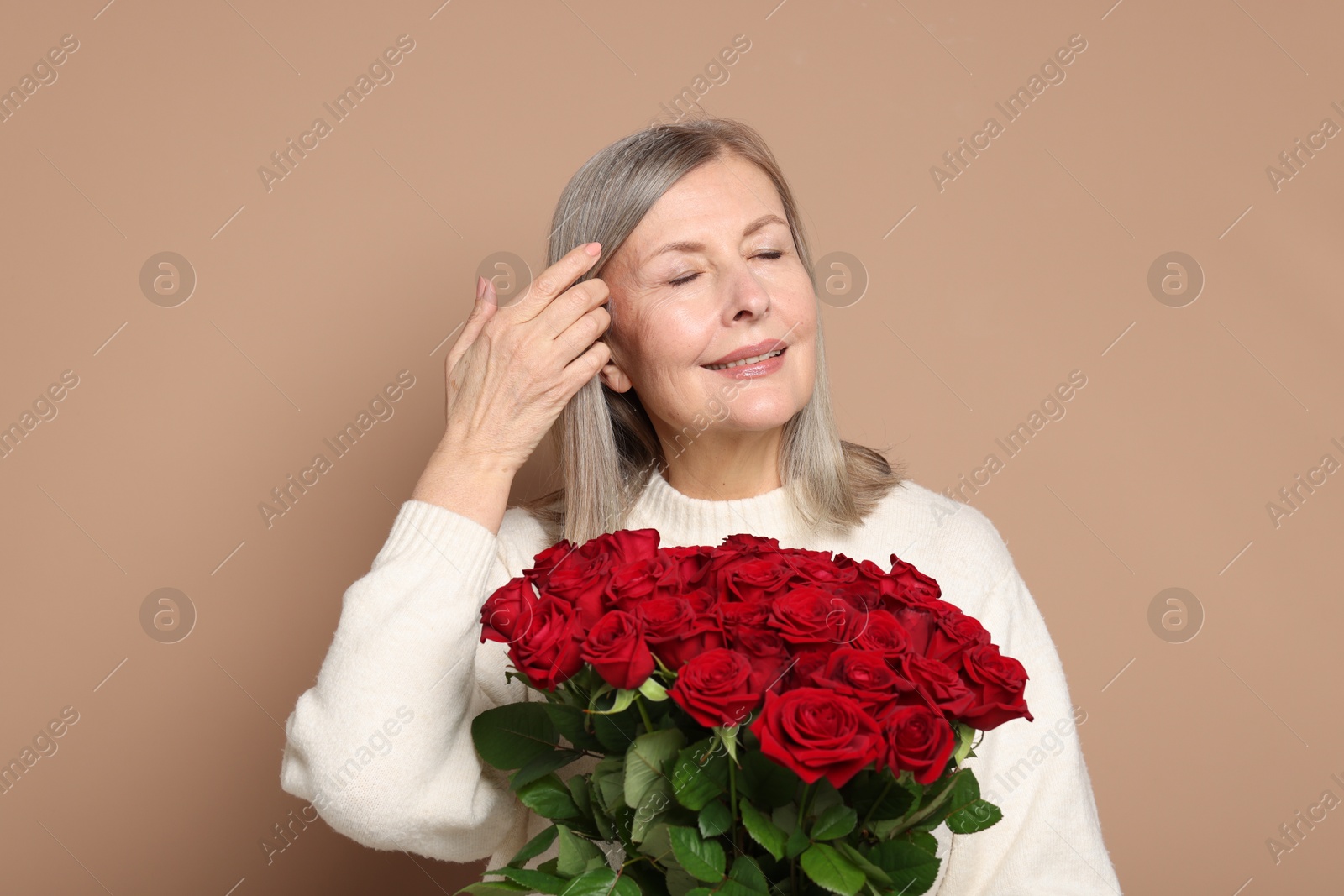 Photo of Smiling woman with bouquet of roses on beige background