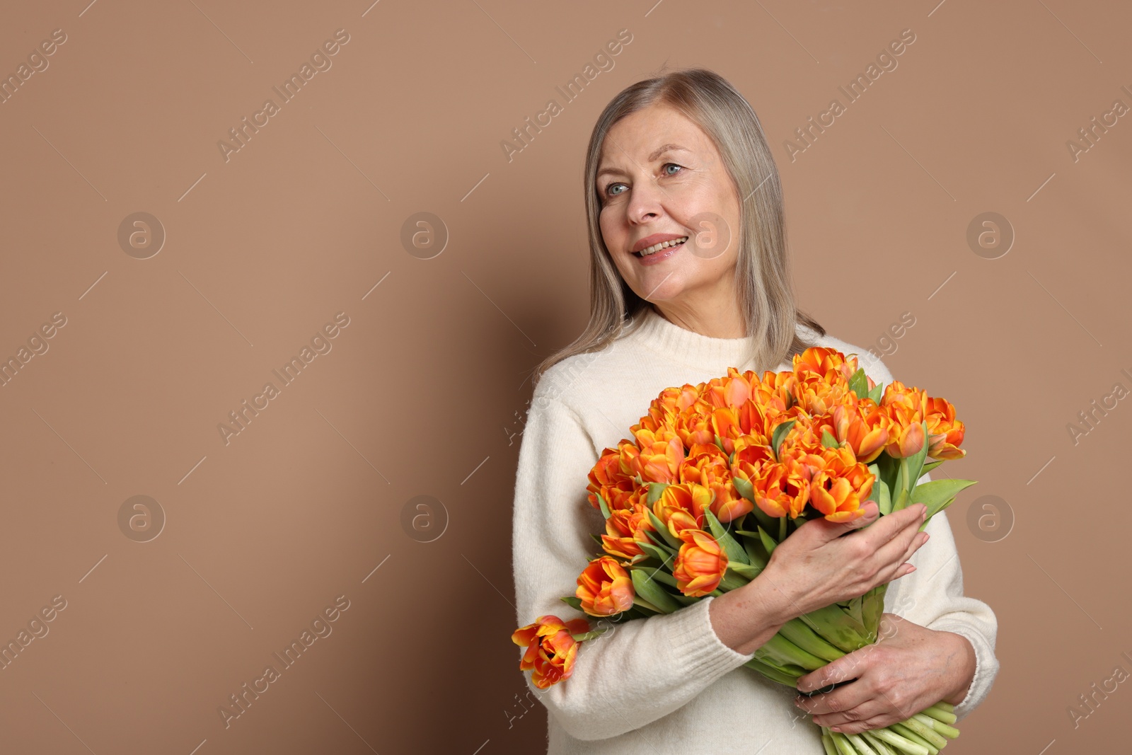 Photo of Smiling woman with bouquet of tulips on beige background. Space for text