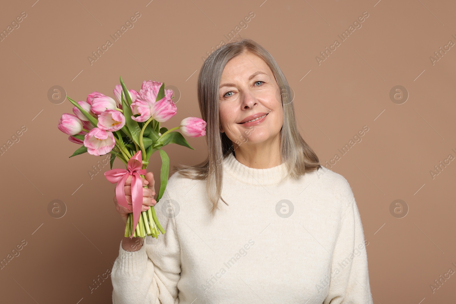 Photo of Smiling woman with bouquet of tulips on beige background