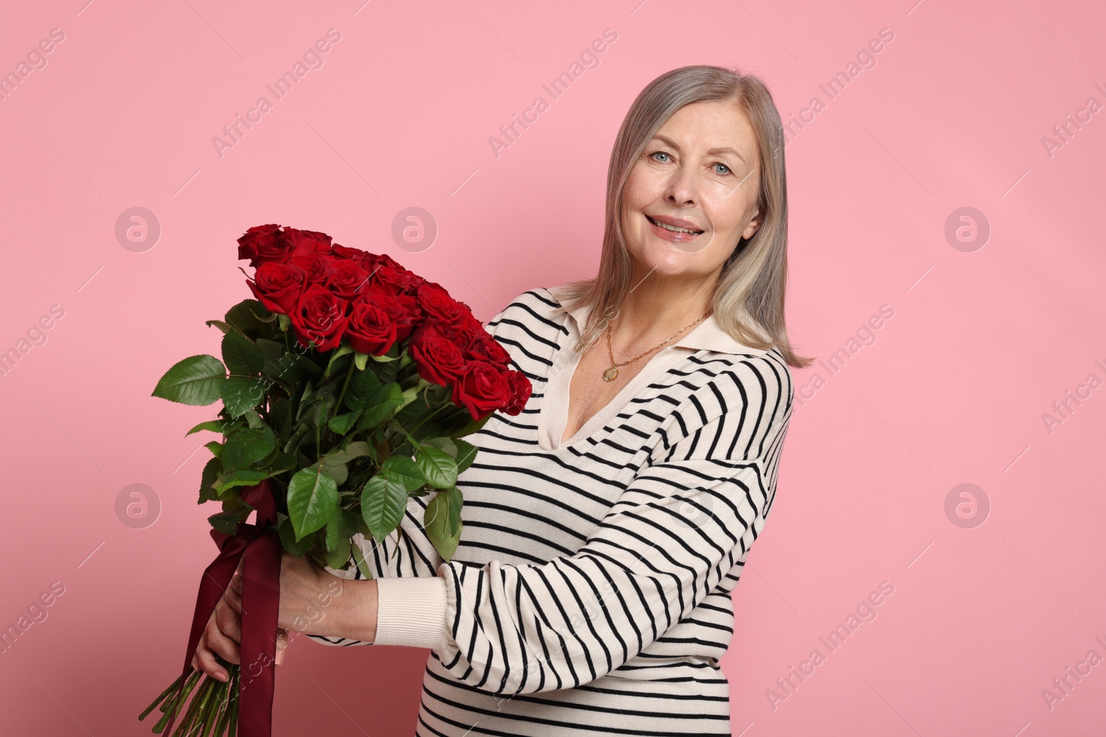 Photo of Smiling woman with bouquet of roses on pink background