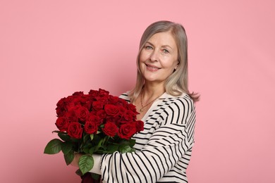 Smiling woman with bouquet of roses on pink background