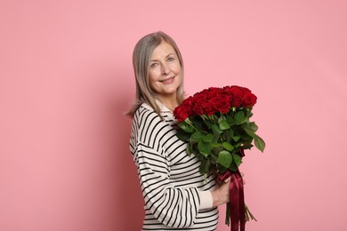 Photo of Smiling woman with bouquet of roses on pink background