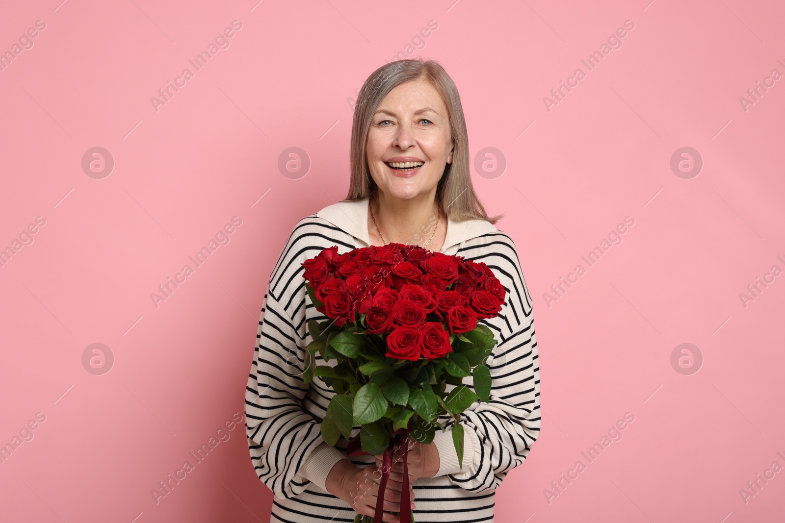 Photo of Smiling woman with bouquet of roses on pink background