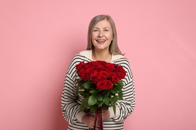 Photo of Smiling woman with bouquet of roses on pink background